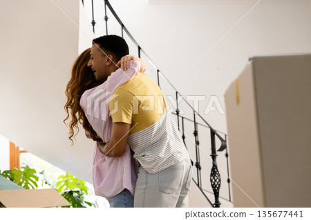 Young couple embracing joyfully while unpacking boxes in new home Young couple embracing joyfully while unpacking boxes in new home 135677441
