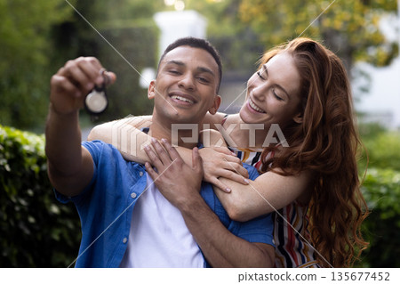 Young couple outdoors holding keys, smiling and celebrating new home together Young couple outdoors holding keys, smiling and celebrating new home together 135677452