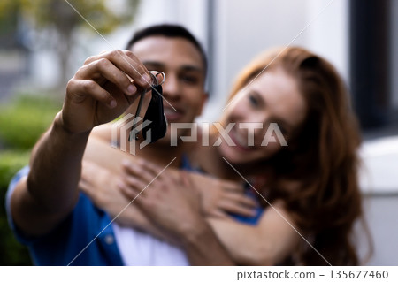 Young couple celebrating new home, holding keys and embracing joyfully outside Young couple celebrating new home, holding keys and embracing joyfully outside 135677460