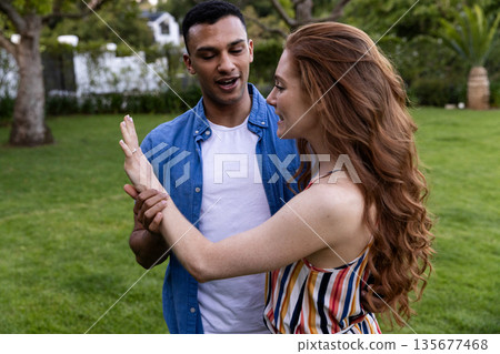 Young couple enjoying playful moment together in lush green park 135677468