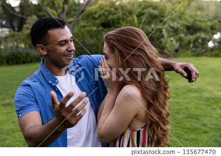 Young couple laughing and embracing in park, enjoying joyful moment together Young couple laughing and embracing in park, enjoying joyful moment together 135677470