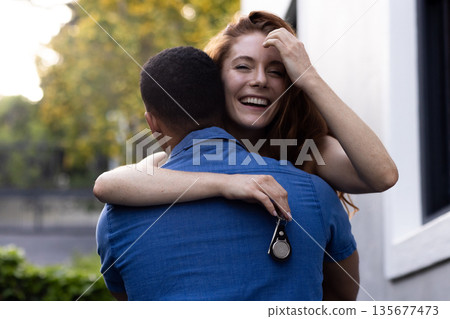 Young couple embracing outdoors, woman smiling joyfully while holding keys Young couple embracing outdoors, woman smiling joyfully while holding keys 135677473