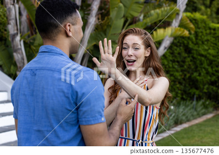 Young couple outdoors, woman joyfully surprised, gesturing with hand, man smiling 135677476