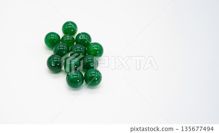 Green onyx round beads on white background, macro photography Green onyx round beads on white background, macro photography 135677494
