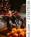 Champagne bottle in an ice bucket with glasses, tangerines in a vase and evergreen branches in background. Elegant New Year festive composition, vertical studio photo. 135678196