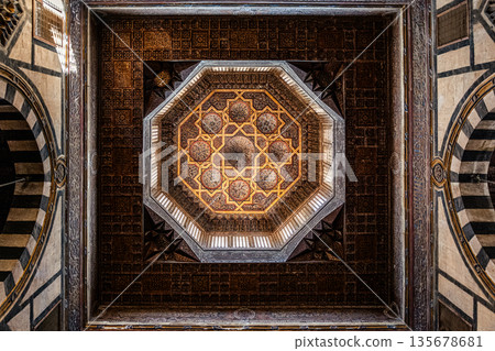 Intricate ceiling design of Sultan Al-Ashraf Qaytbay Mosque. Features geometric patterns and ornate details in gold and brown tones Intricate ceiling design of Sultan Al-Ashraf Qaytbay Mosque. Features geometric patterns and ornate details in gold and brown tones 135678681