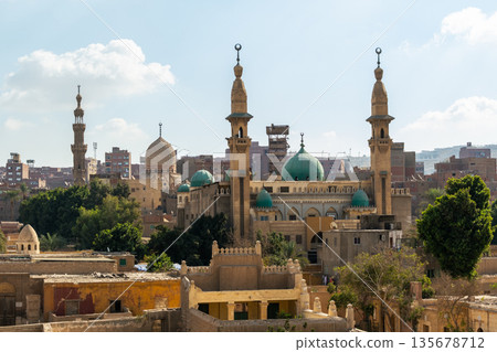 A panoramic view of the City of the Dead in Cairo, featuring ancient tombs, mosques, and minarets under a clear blue sky. A panoramic view of the City of the Dead in Cairo, featuring ancient tombs, mosques, and minarets under a clear blue sky. 135678712