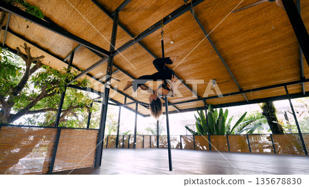 Aerial dancer performing acrobatics in tropical yoga studio Aerial dancer performing acrobatics in tropical yoga studio 135678830