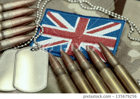 Rows of military cartridges and metal identification tags placed on United Kingdom flag fabric. Rows of military cartridges and metal identification tags placed on United Kingdom flag fabric. 135679256