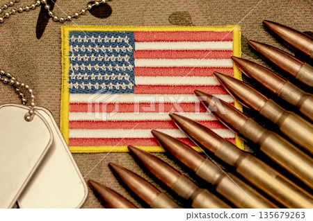 Ammunition and army tags on camouflage fabric with American flag. Ammunition and army tags on camouflage fabric with American flag. 135679263