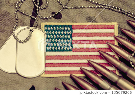 Army ammunition and metal tags on camouflage background with United States flag. Army ammunition and metal tags on camouflage background with United States flag. 135679266