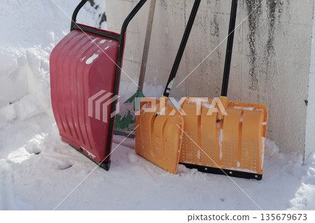 A mom's dump truck and shovel leaning against a snow-covered wall 135679673