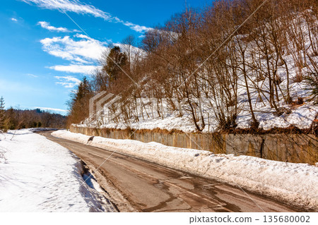 country road winding through winter landscape under blue sky. great bereznyi district of carpathian mountains on a sunny day. scenic view of uzhanian pass. travel background with snow covered slopes 135680002