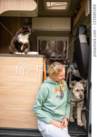 Woman traveling with dog and cat inside camper van doorway during outdoor road trip 135680169