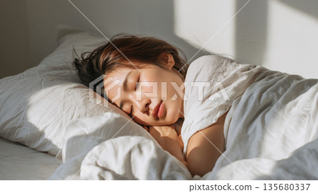 A young woman sleeping in bed 135680337