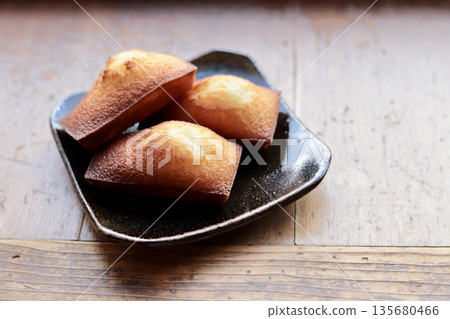 新鮮出爐、酥脆蓬鬆的費南雪蛋糕,盛放在日式盤子裡。 新鮮出爐、酥脆蓬鬆的費南雪蛋糕,盛放在日式盤子裡。 135680466