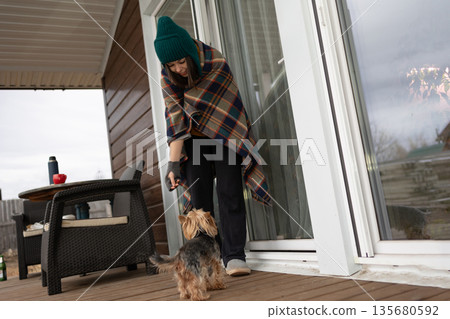 Young Woman Playing With a Yorkshire Terrier on Her Porch in Autumn Young Woman Playing With a Yorkshire Terrier on Her Porch in Autumn 135680592