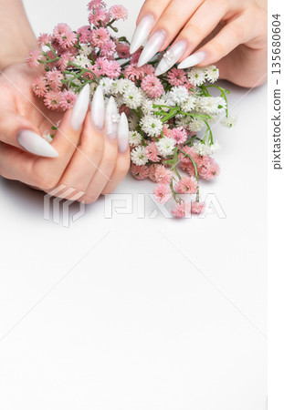 Woman's hands holding flowers with stiletto nail art manicure Woman's hands holding flowers with stiletto nail art manicure 135680604