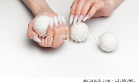 Woman hands holding sparkling christmas ornaments with long nails 135680605