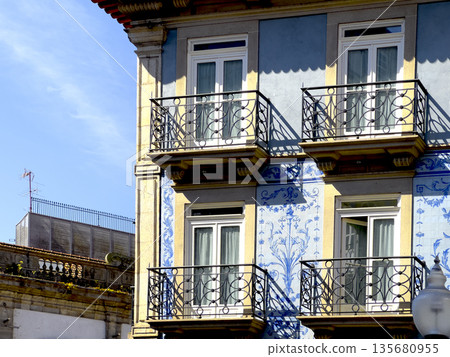 Traditional Portuguese building with blue azulejo tiles, ornate balcony and classic window details. Traditional Portuguese building with blue azulejo tiles, ornate balcony and classic window details. 135680955