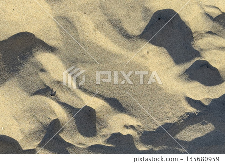 Sandy desert dune landscape with soft ripples and warm beige tones under bright sunlight. Peaceful 135680959