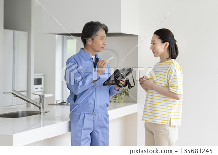 A middle-aged woman listening to the explanation of a contractor holding a tablet A middle-aged woman listening to the explanation of a contractor holding a tablet 135681245