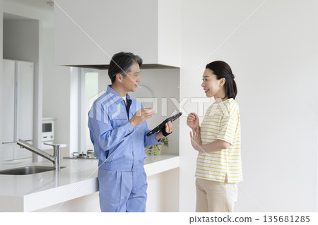 A middle-aged woman listening to the explanation of a contractor holding a tablet A middle-aged woman listening to the explanation of a contractor holding a tablet 135681285