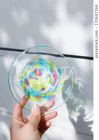 A woman's hand picking up a glass plate in the soft sunlight filtering through the trees A woman's hand picking up a glass plate in the soft sunlight filtering through the trees 135681564