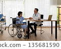 Doctor gently holding the hand of an elderly female patient in a wheelchair during a hospital consultation. Scene shows trust, empathy, and compassionate care in a clinic 135681590
