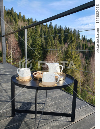 Two cups of hot cocoa on a small table on the terrace, with a view of the Carpathian Mountains. Two cups of hot cocoa on a small table on the terrace, with a view of the Carpathian Mountains. 135682018