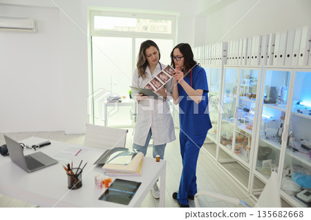 Collaboration in a modern medical office as professionals discuss patient treatment options and medical images together 135682668