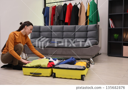 Preparing for a stylish journey with colorful outfits in a cozy living room setting 135682876