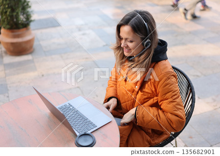 Enjoying a productive work session outdoors on a sunny day with laptop and coffee in a cozy cafe setting Enjoying a productive work session outdoors on a sunny day with laptop and coffee in a cozy cafe setting 135682901