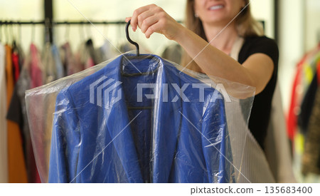 Choosing the perfect blue jacket while shopping in a stylish clothing store on a sunny afternoon Choosing the perfect blue jacket while shopping in a stylish clothing store on a sunny afternoon 135683400