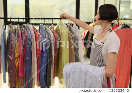 Sorting colorful garments in a bustling clothing store during a bright afternoon 135683440