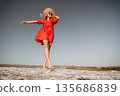 Woman in Red Dress Walks on a Rocky Path 135686839