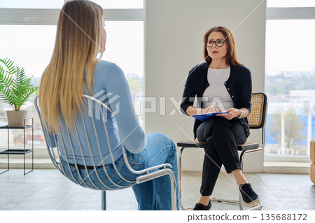 Middle aged professional female psychologist, counselor working with young woman Middle aged professional female psychologist, counselor working with young woman 135688172