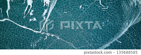 Aerial view of cracked ice on dark blue lake water. Banner Aerial view of cracked ice on dark blue lake water. Banner 135688585