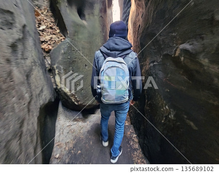 Hiker Walking Through Narrow Rocky Canyon 135689102