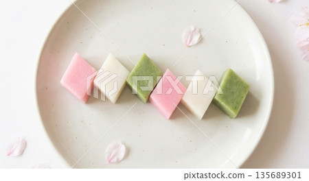 三種顏色的菱形日式年糕點點心，充滿春天的氣息，精美地擺放在白色盤子上。 135689301