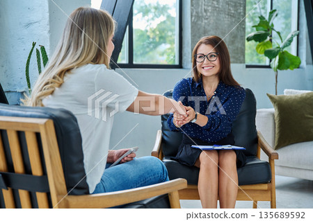 Middle aged professional female psychologist, counselor working with young woman 135689592