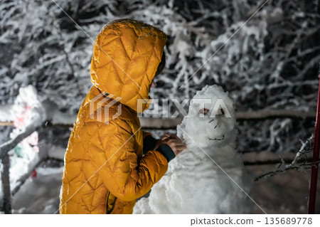 Boy Making a Snowman at Night Boy Making a Snowman at Night 135689778
