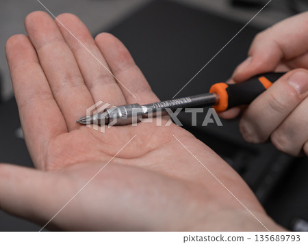 Hand holding an adjustable screwdriver with a Phillips head bit, ideal for precise repair and assembly tasks or various DIY projects Hand holding an adjustable screwdriver with a Phillips head bit, ideal for precise repair and assembly tasks or various DIY projects 135689793