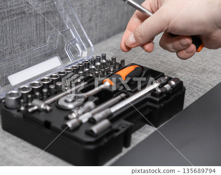 A person's hand selects a precision screwdriver from an open professional toolkit, symbolizing reliable home improvement, repair, and expert craftsmanship for various tasks 135689794