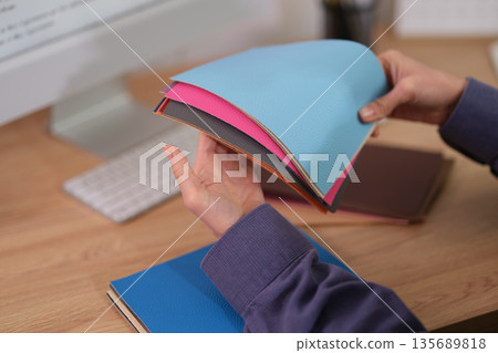 Creative hands explore colorful sheets of paper in a cozy workspace filled with inspiration and design possibilities Creative hands explore colorful sheets of paper in a cozy workspace filled with inspiration and design possibilities 135689818