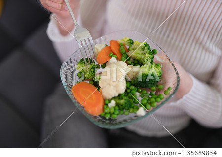 Colorful vegetable medley served on a glass plate in a cozy living room setting 135689834