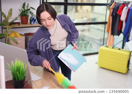 Bright and lively workspace comes to life as a woman tidies and organizes her creative space with care and attention Bright and lively workspace comes to life as a woman tidies and organizes her creative space with care and attention 135690005