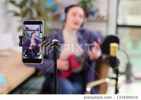 Musician shares joyful moments through melody while recording in a cozy home studio 135690029