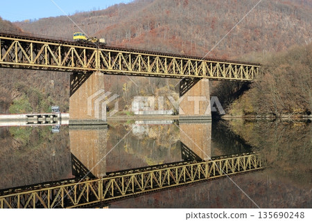 A bridge spans a river with a train crossing it A bridge spans a river with a train crossing it 135690248