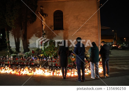A group of people are gathered around a shrine with candles lit 135690250